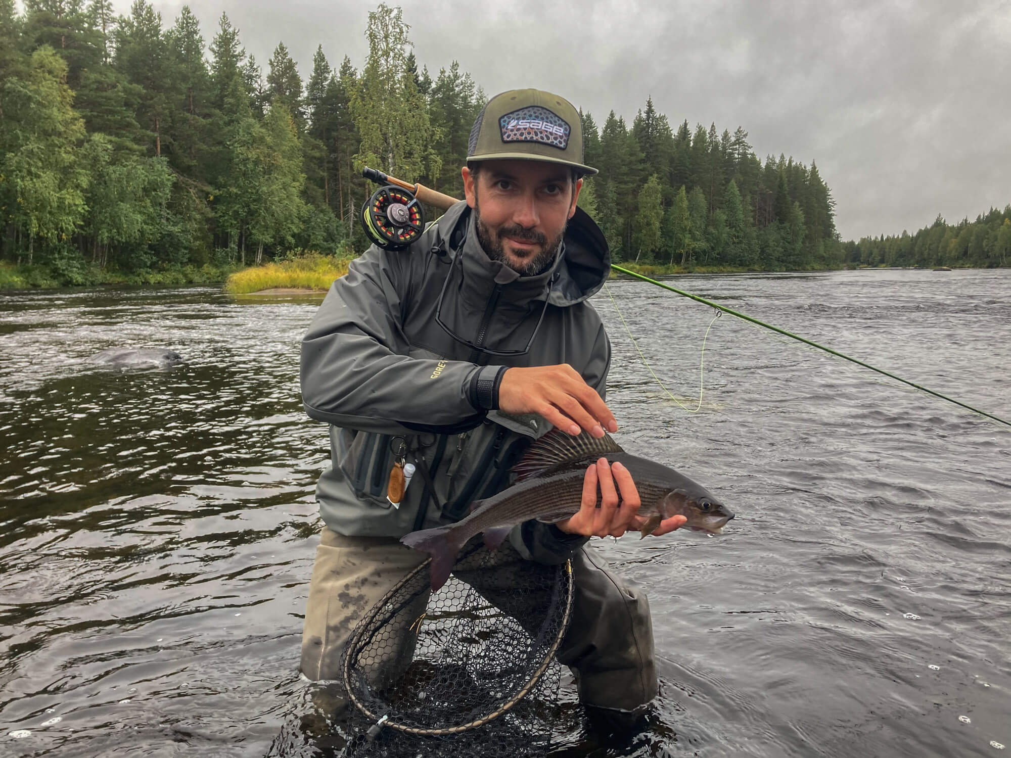 Un pêcheur posant avec un ombre en rivière