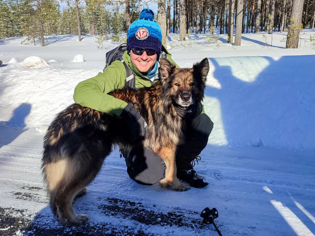 Bien s'habiller pour le grand froid, un skieur pose avec un berger allemand en Laponie suédoise