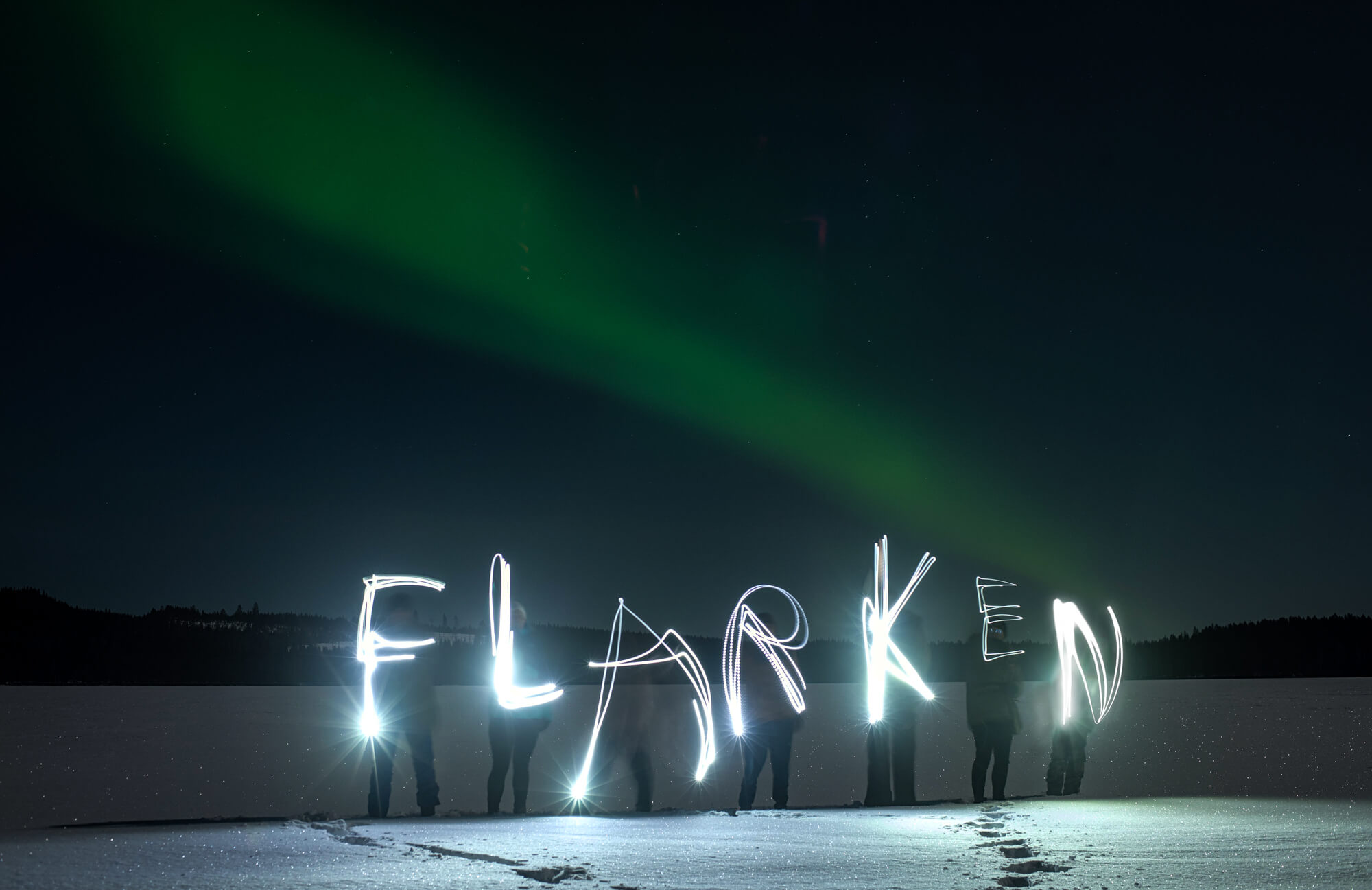 questions-reponses-suede-laponie-flarken-adventure-398 Flarken écrit avec des torches devant des aurores boréales en Laponie